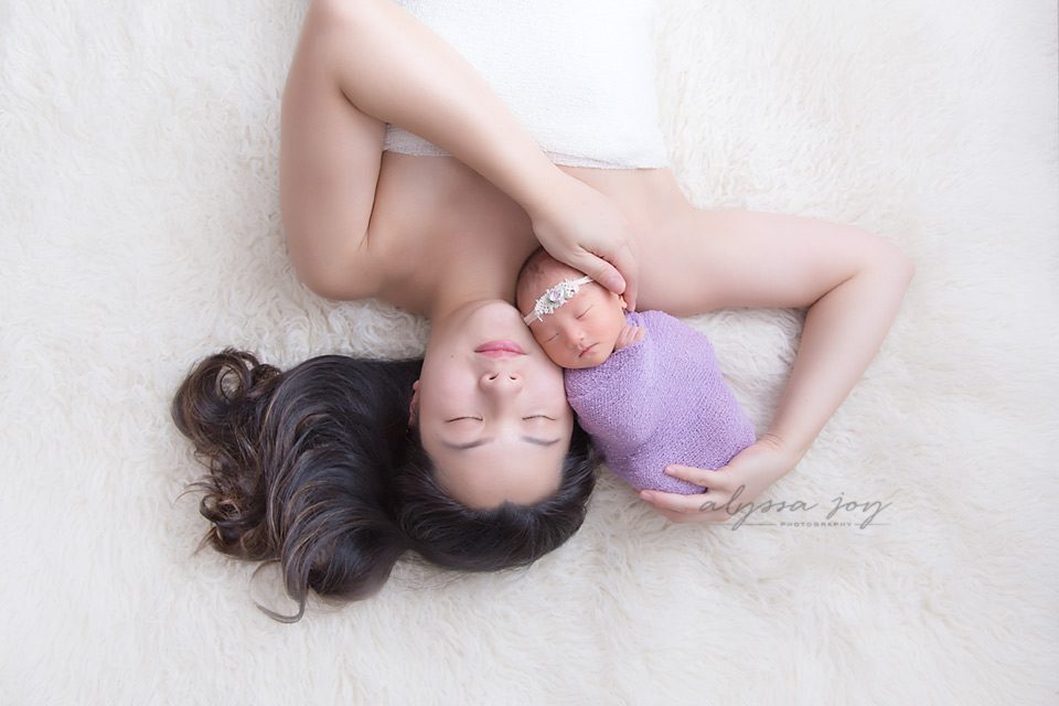 asian mom and newborn baby girl on flokati rug wrapped in purple