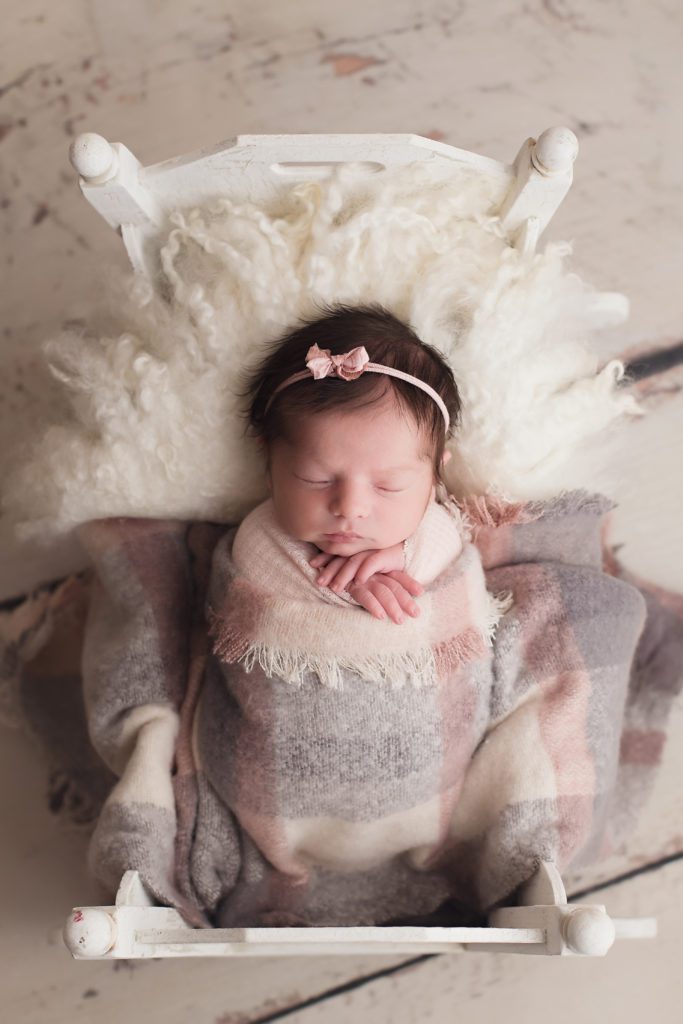 newborn baby girl portrait in cradle with pink grey and cream Alyssa Joy Photography