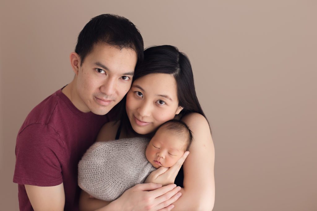portrait of new mom and dad holding newborn baby boy
