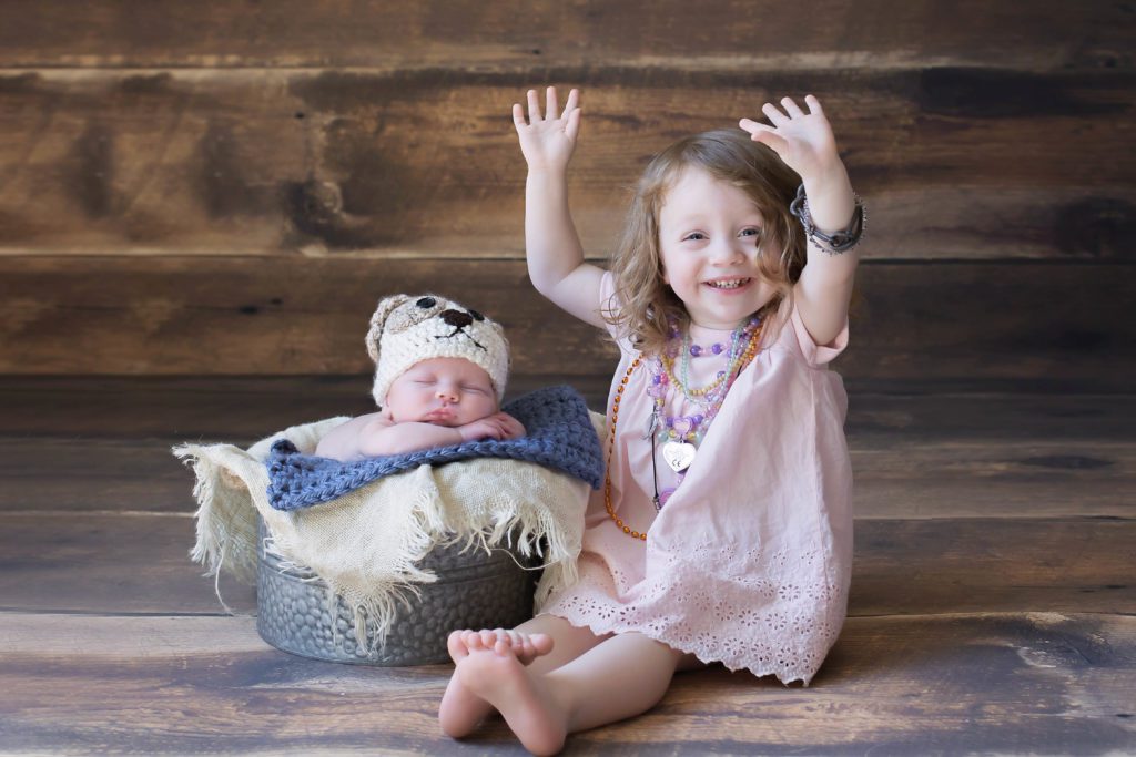 photo of baby boy newborn portrait session wearing a puppy hat with big sister