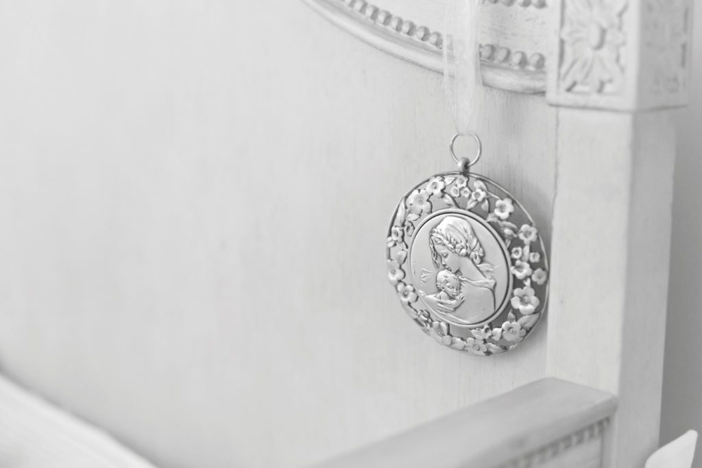 detail picture of newborn baby's crib and religious medallion hanging in crib