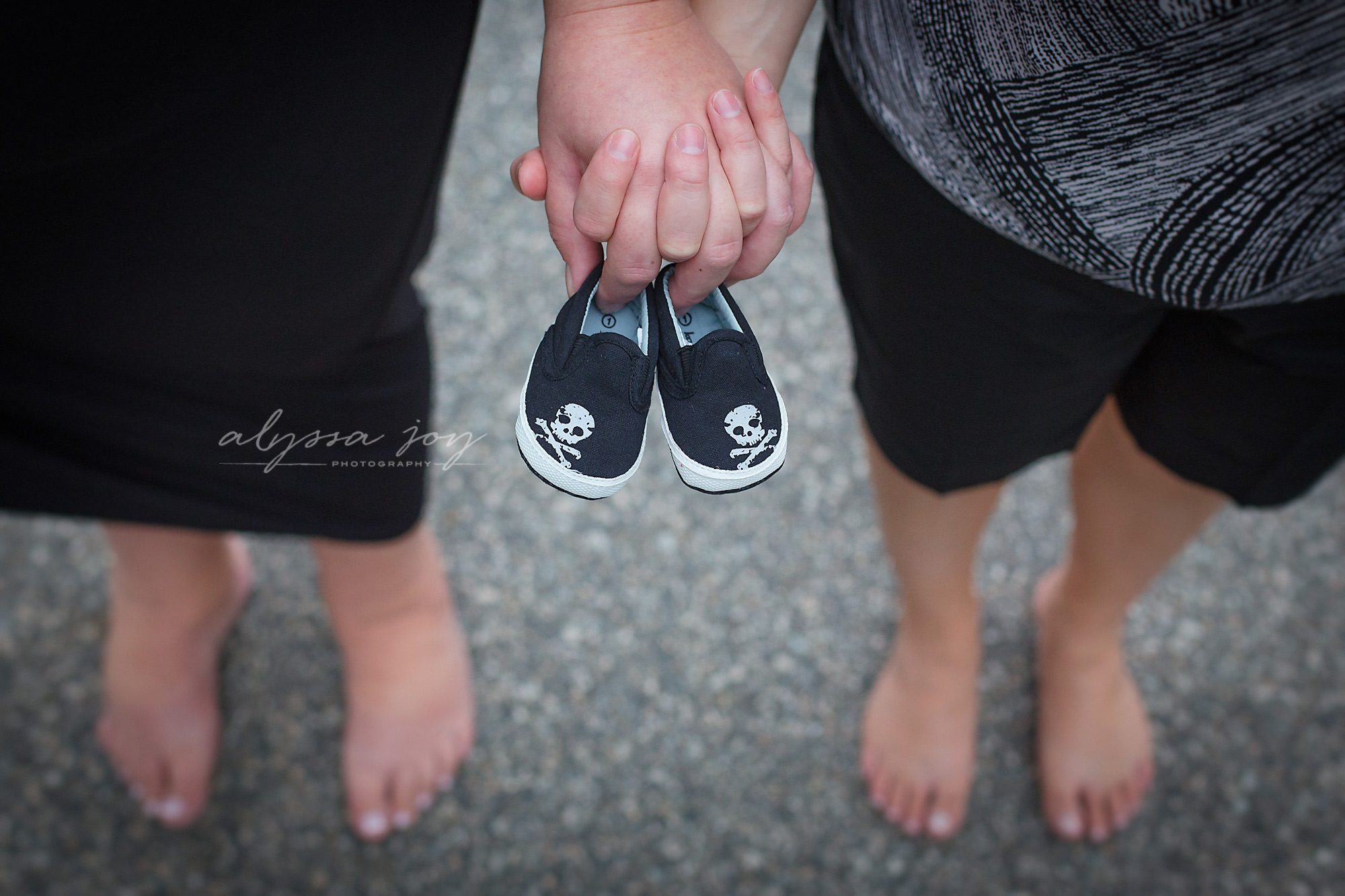 photo of mommies to be holding hands and tiny baby shoes of their expecting baby boy