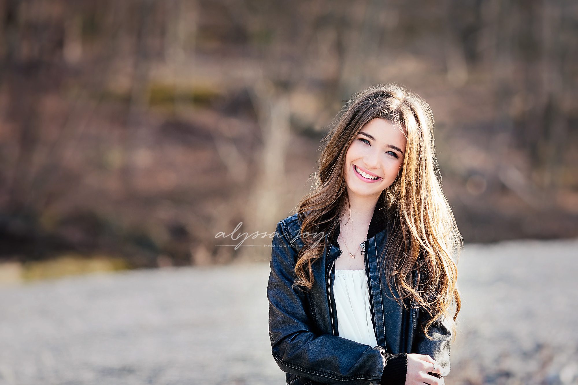 sunny shot of teenage girl with long hair smiling and posing for Alyssa Joy Photography