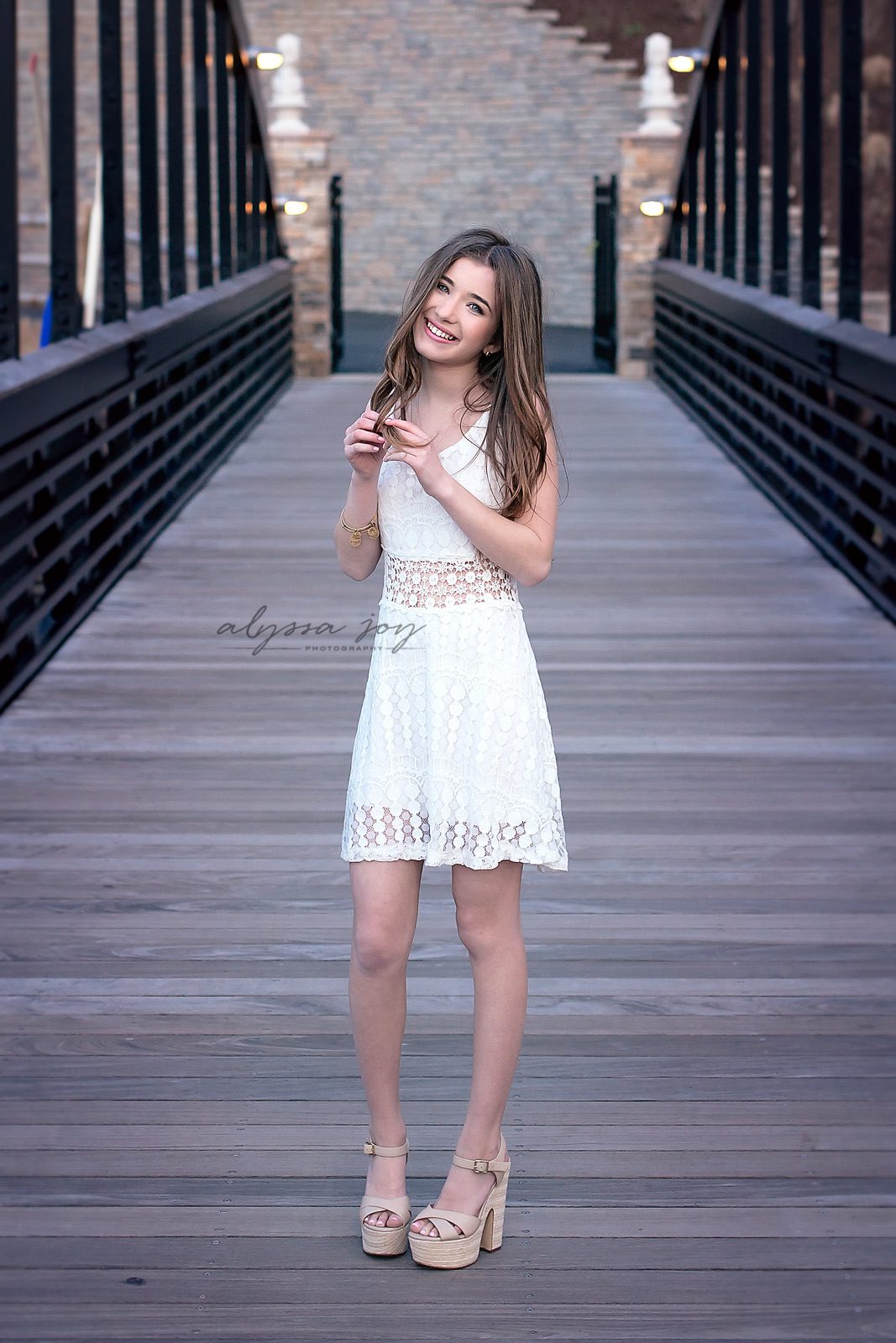 teenage girl posing in lace white dress on boardwalk 
