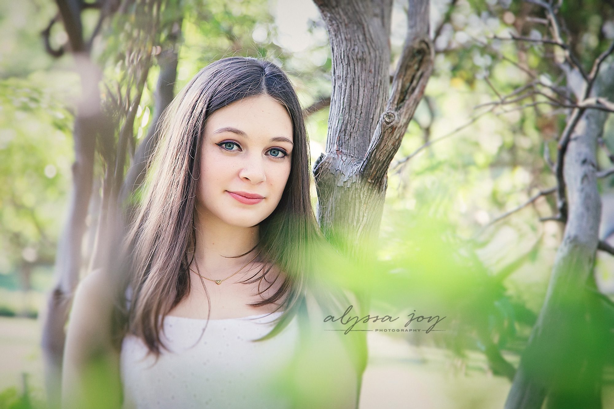 photo of teenage girl posing among trees at park taken by Alyssa Joy Photography