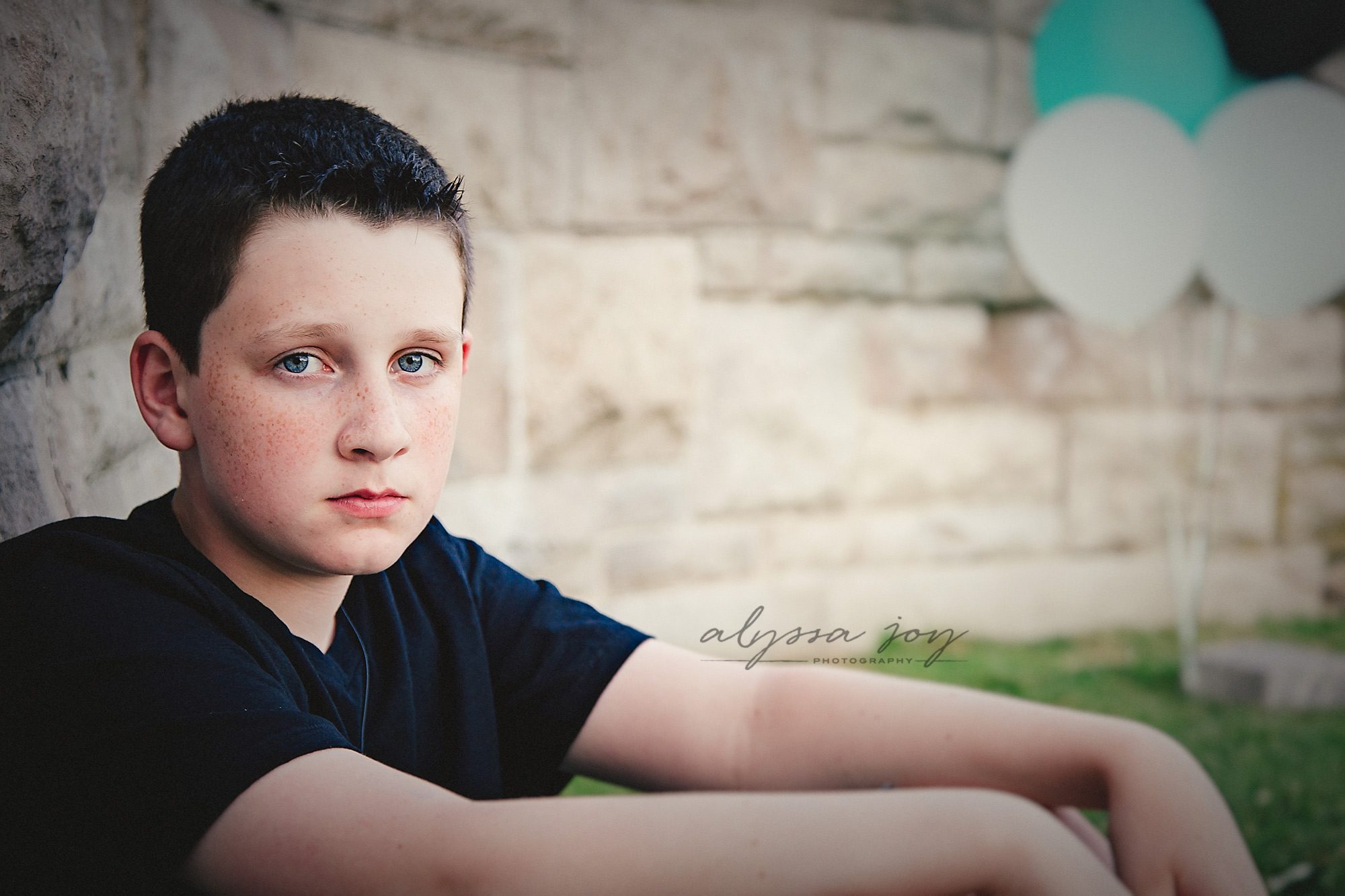 serious shot of teenage boy posing by brick wall Alyssa Joy Photography