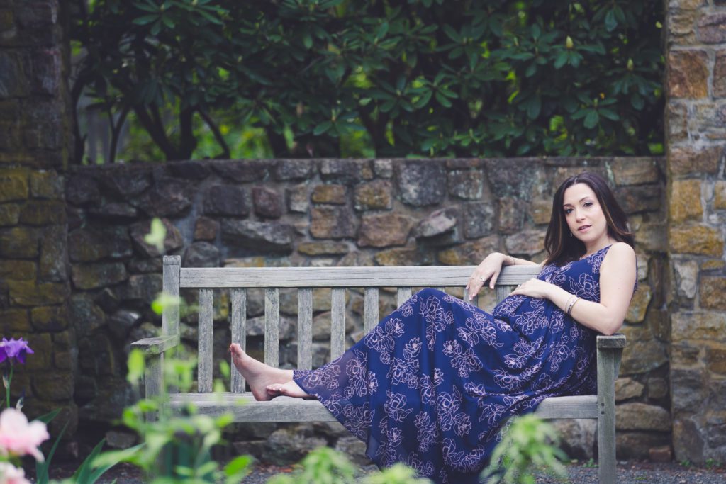 maternity portrait session with new mom to be on bench and flowing dress