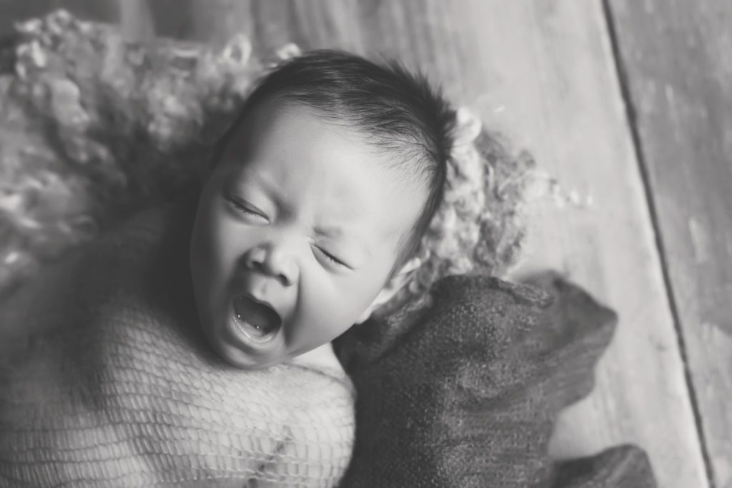 black and white photo of newborn baby yawning at newborn photo session
