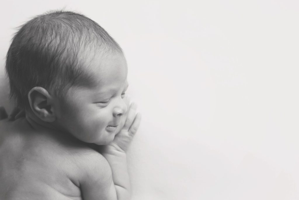 black and white photo of newborn baby boy's profile smiling 