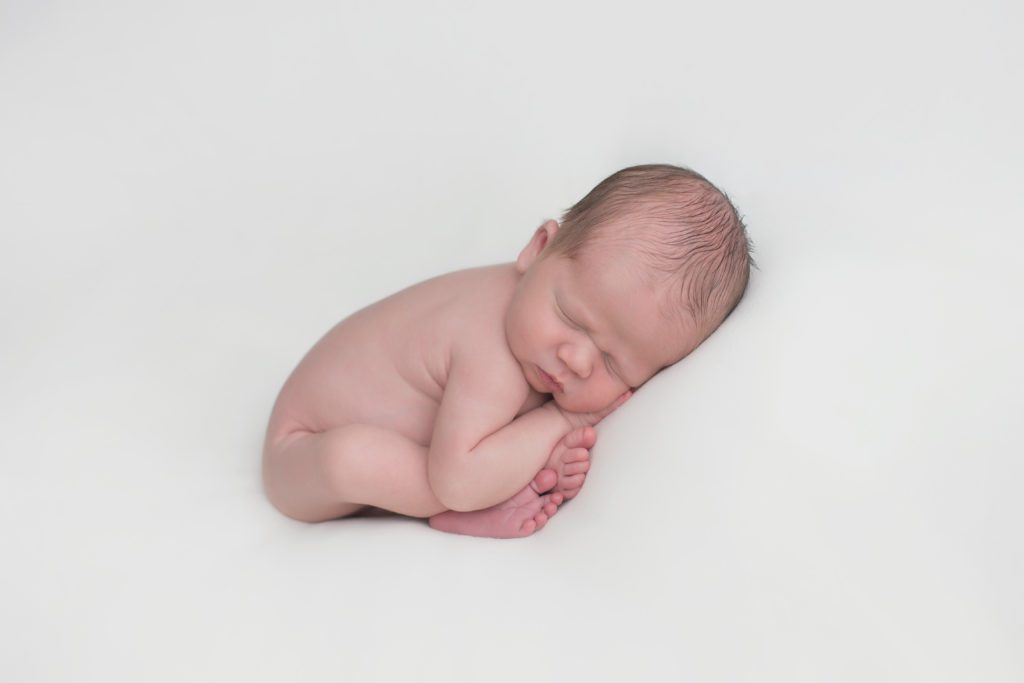 newborn baby boy in taco pose on white fabric backdrop Alyssa Joy Photography