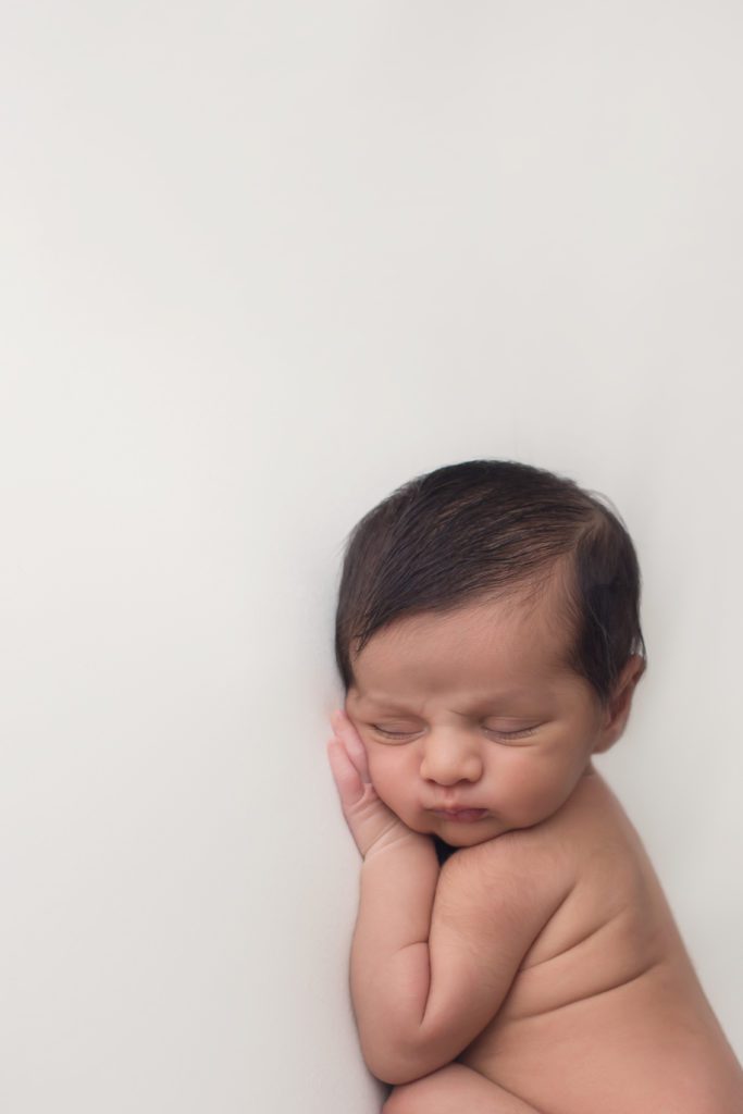 portrait orientation of newborn baby boy sleeping on white background by Alyssa Joy Photography