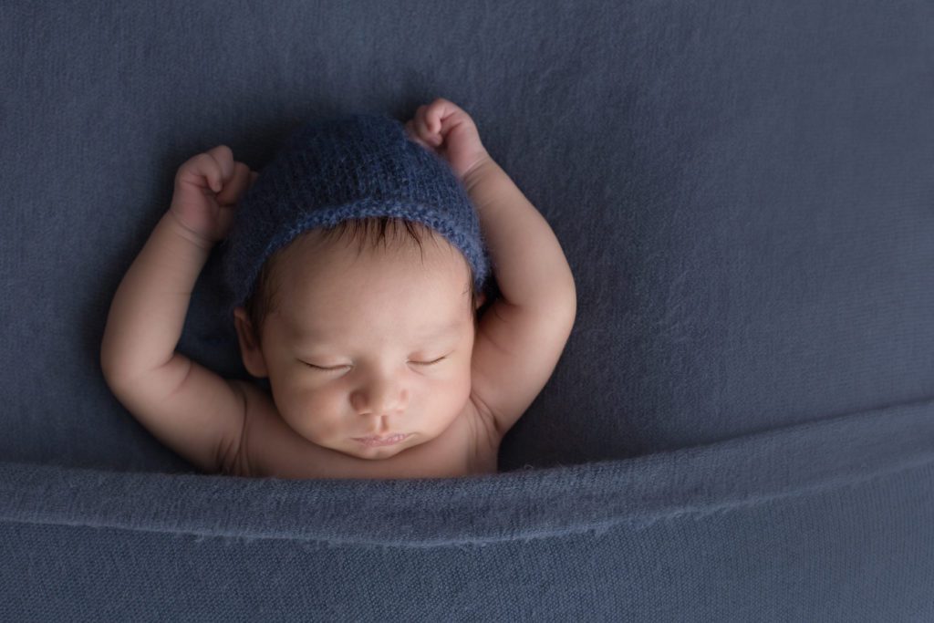 baby boy 3 weeks old newborn photo in simple pose with arms up laying on navy fabric Alyssa Joy Photography
