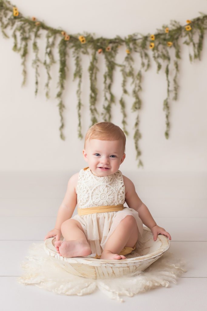 one year old girl in cream and yellow outfit for milestone photo session