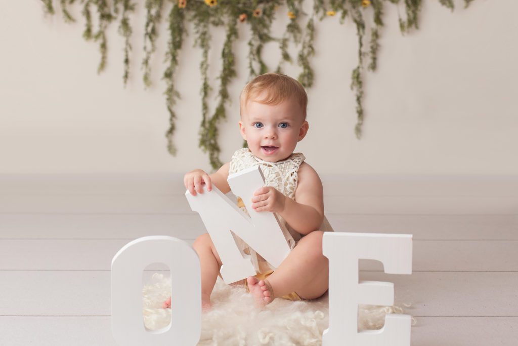 baby girl posing with ONE letters for her first birthday portrait session