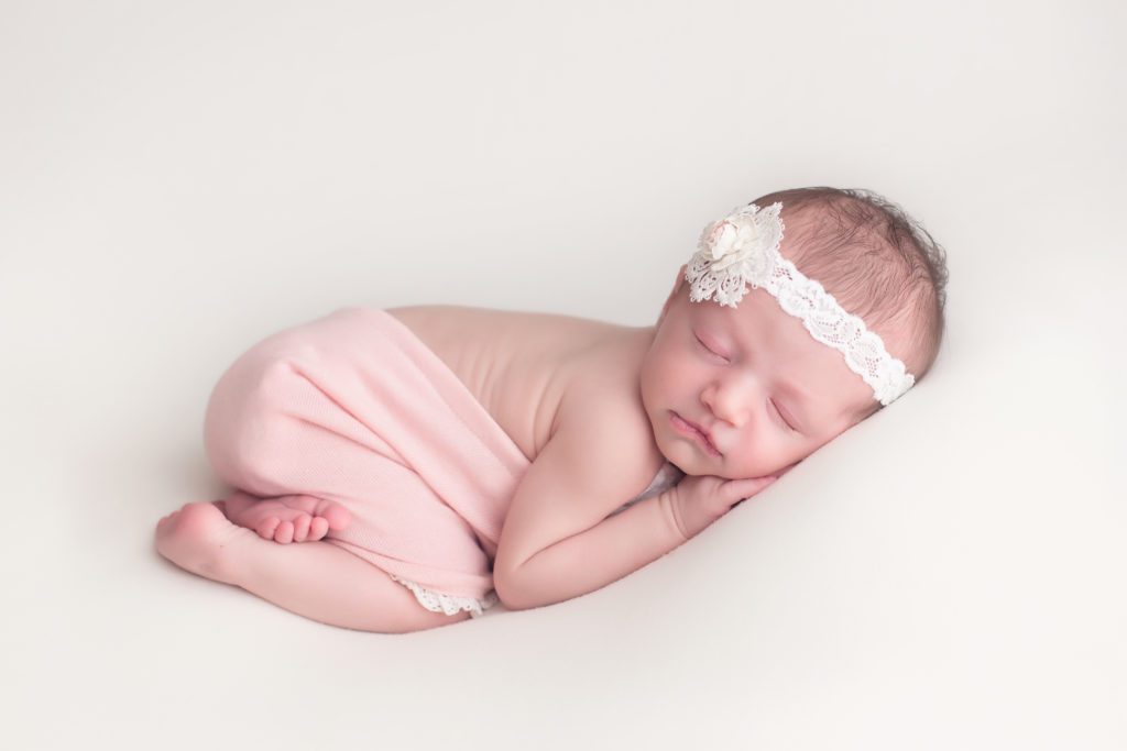 newborn baby girl in tushie up pose on white backdrop