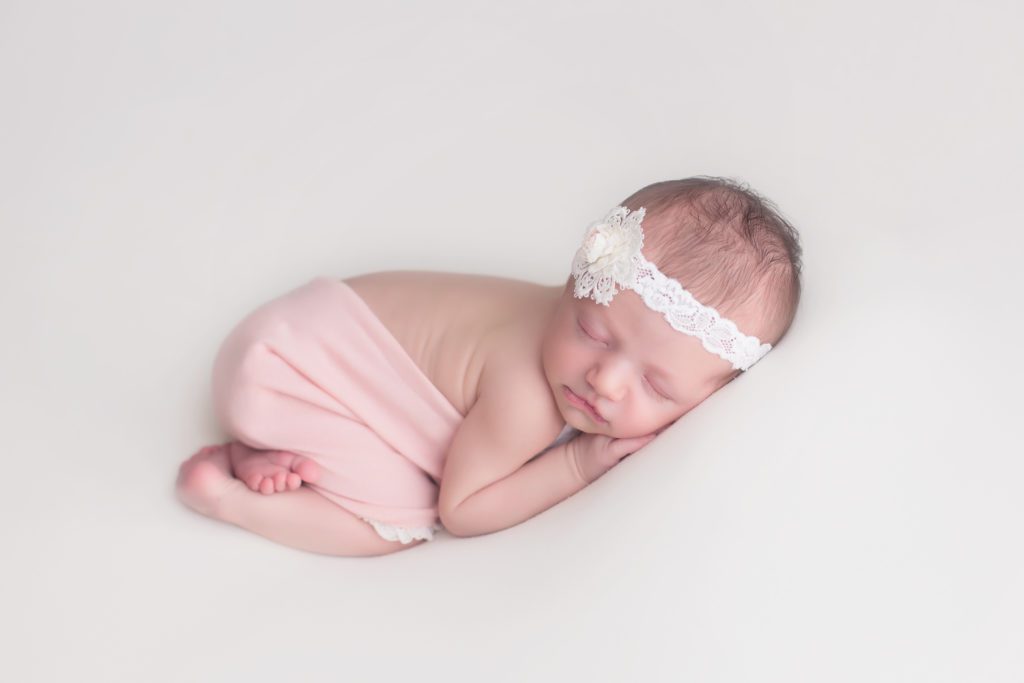 tushie up pose of baby girl at newborn photo session dressed in pink romper