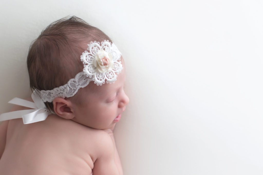 side profile of newborn baby girl with headband and white bow