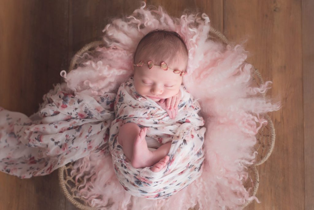 baby girl newborn session wrapped in floral wrap in pink basket