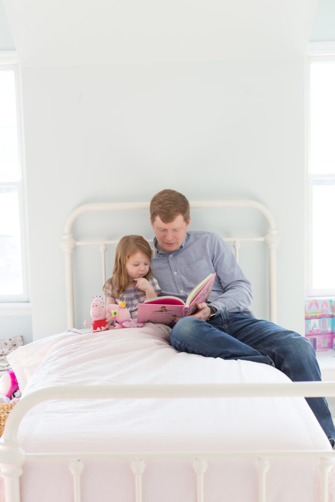 picture of dad reading princess stories to his 3 year old daughter at lifestyle newborn session