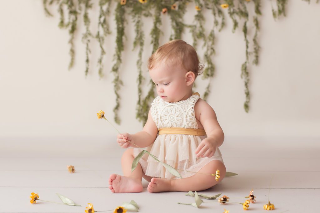 one year old girl holding flower to match her lace romper