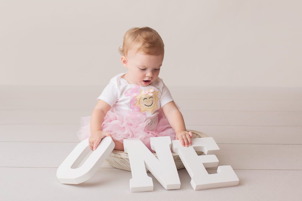 ONE wood letters held by little girl who just turned one wearing a pink tulle skirt