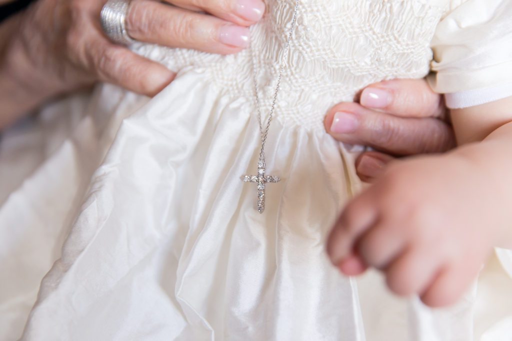 photo of baby's new diamond cross with grandmother's hand holding baby 