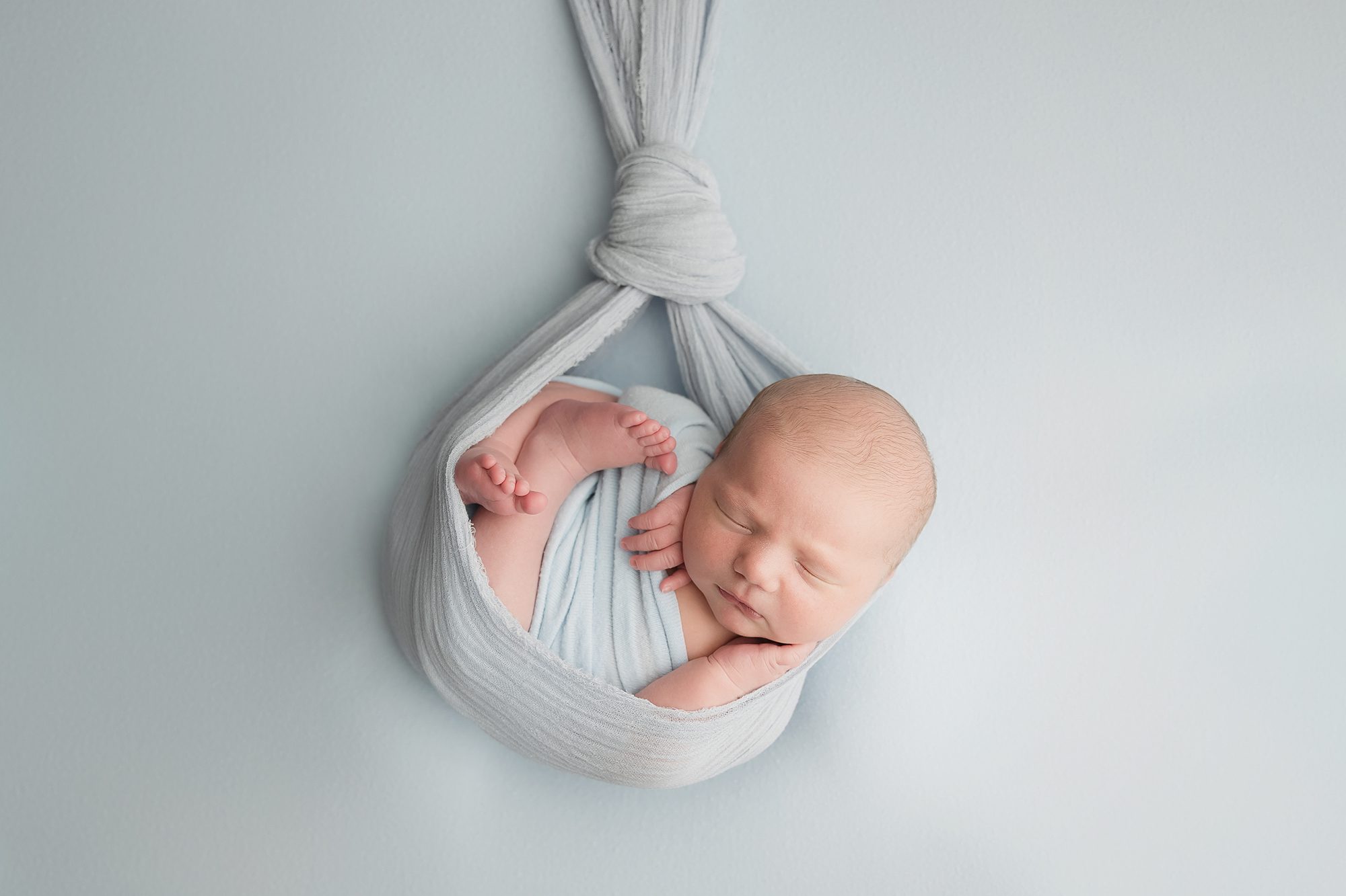 newborn boy posed and wrapped in baby blue