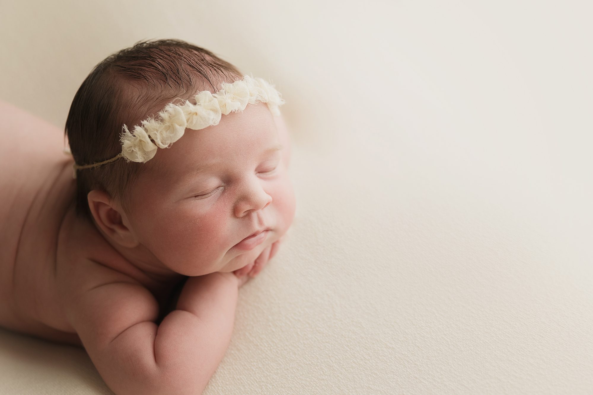 newborn baby girl side profile on neutral fabric