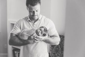 dad holding newborn baby boy in nursery lifestyle session Alyssa Joy Photography