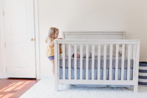 big sister peeking into newborn crib lifestyle session Alyssa Joy